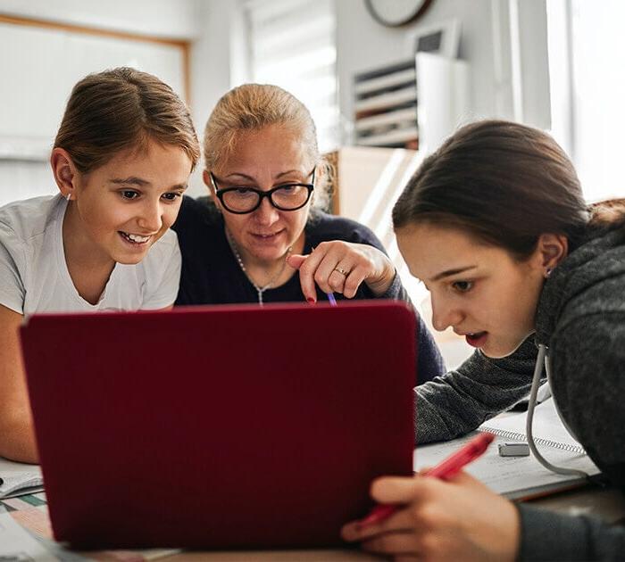 A mother and two daughters are looking at a laptop together